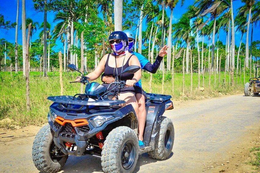 A person riding an ATV on a dirt road with palm trees in the background. 4