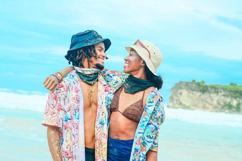 A couple on a beach with a clear sky and ocean in the background. 2