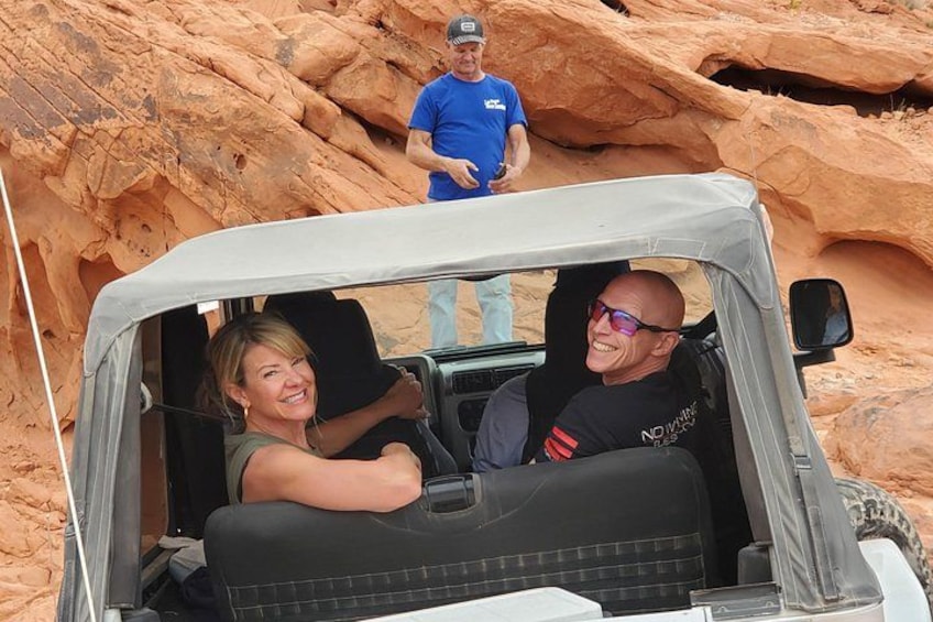 A vehicle parked in a rocky canyon with a person standing in the background. 3