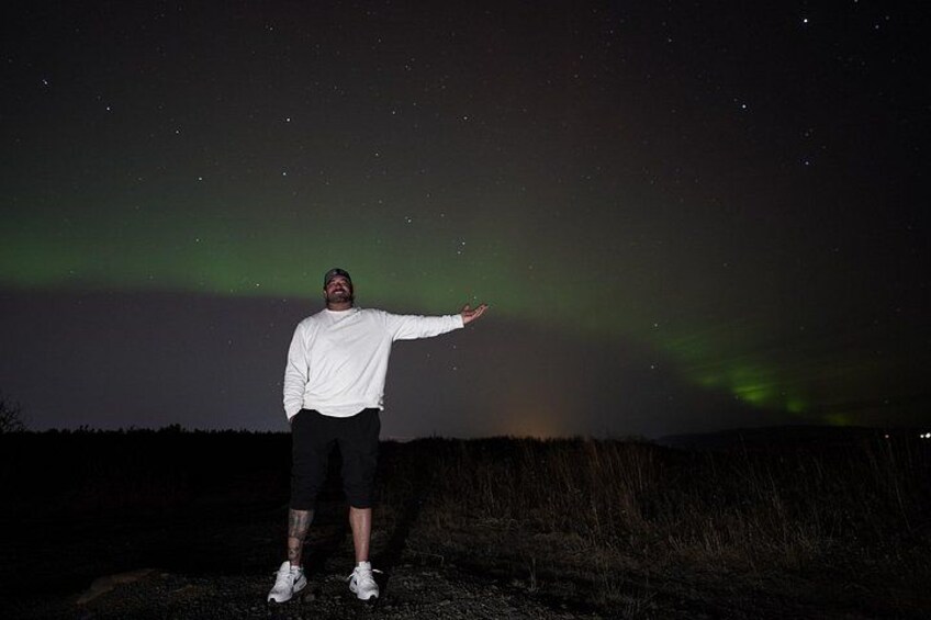 A person standing on a dirt path under a night sky with visible stars and the aurora borealis. 5