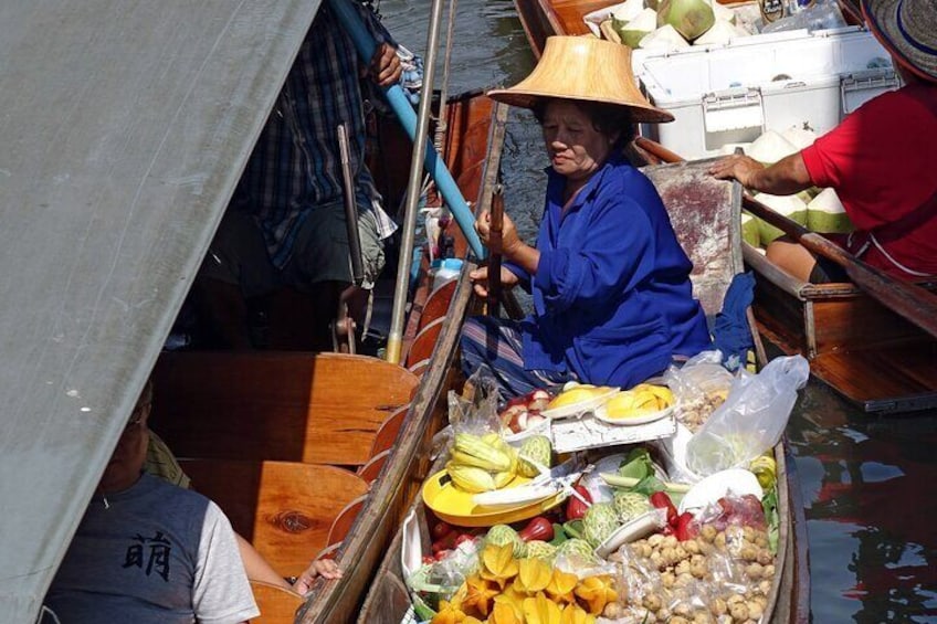 Une personne se trouve dans un bateau, tenant un grand parapluie et un bâton bleu, et est entourée de divers fruits et légumes. 3