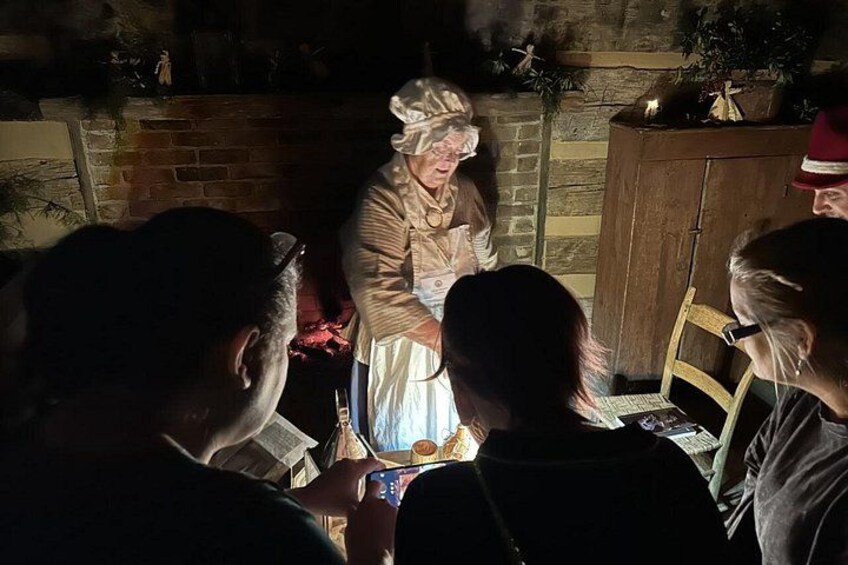En person i historisk kostume står ved et bord omringet af en menneskemængde. 4