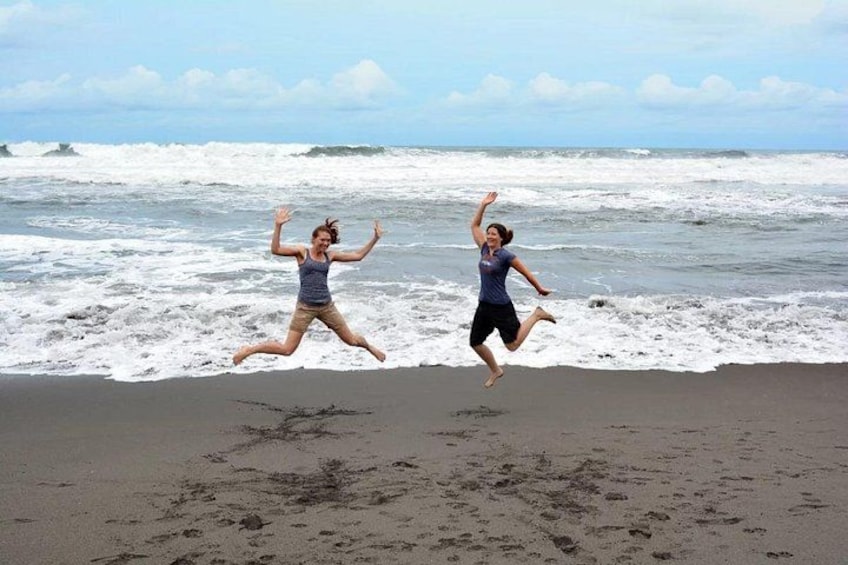 Two people jumping on a beach with waves in the background. 4