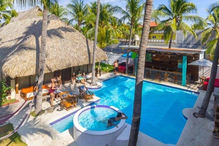 A pool area with lounge chairs, a hot tub, and palm trees. 2