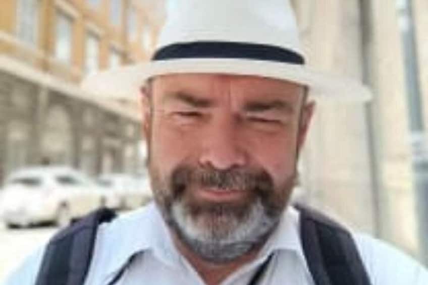 Eine Person trägt einen weißen Hut, ein weißes Hemd und eine schwarze Weste. 3