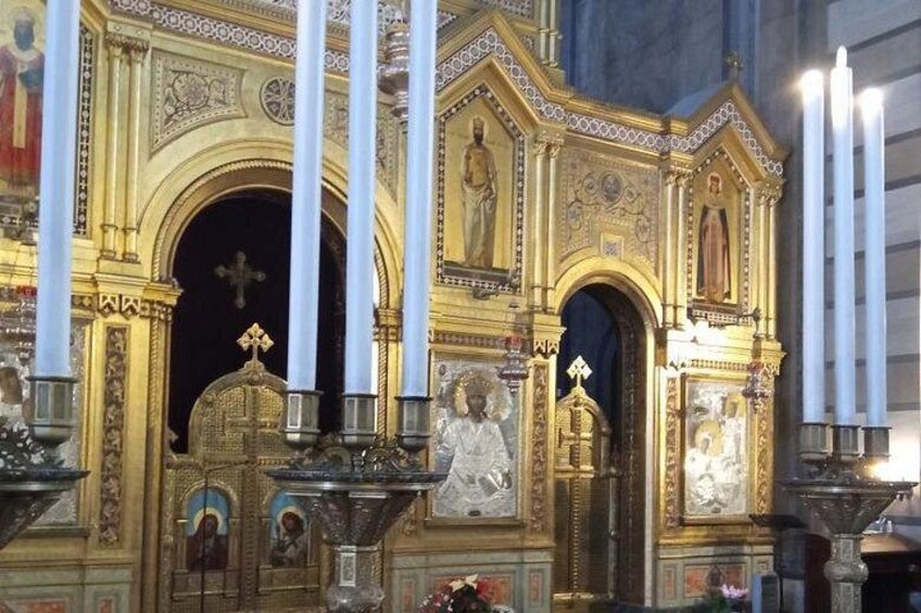 Ein Kircheninneres mit aufwendiger goldener Dekoration, einem großen Kruzifix und zahlreichen Kerzen. 2