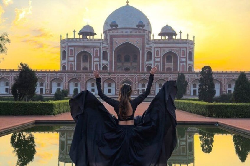 A person standing in front of the Taj Mahal with arms raised, reflecting on the water. 1
