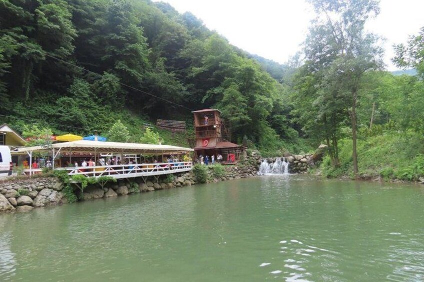 A river with a wooden bridge, a boat dock, and a waterfall. 2