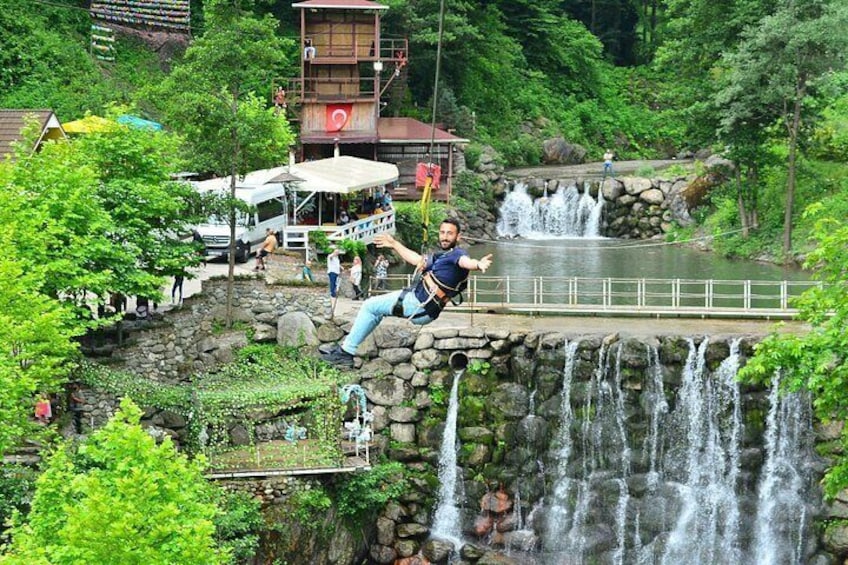 Una persona haciendo bungee jumping desde un puente, con una cascada al fondo. 4