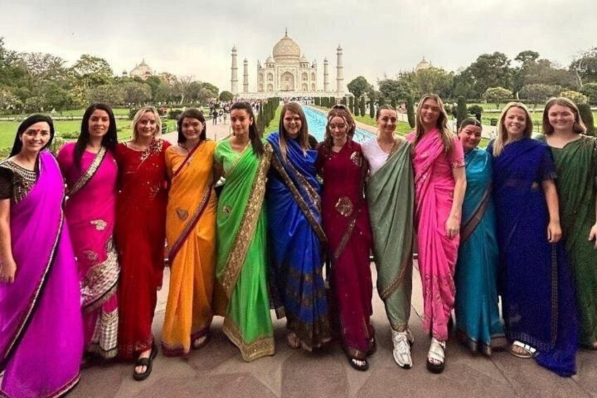 Un groupe de personnes, vêtues de costumes traditionnels aux couleurs vives, se tient devant le Taj Mahal. 5