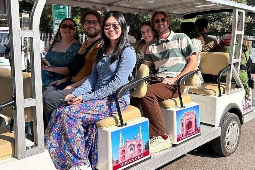 Eine Gruppe von Personen fährt mit einem Sightseeing-Trolley und hat einen Blick auf ein Gebäude. 2