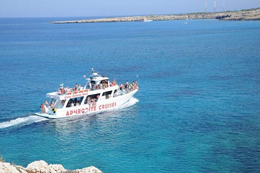 En hvid båd med rød tekst 'APHRONITE CRUISES' på siden sejler på et stille, blåt hav. 3