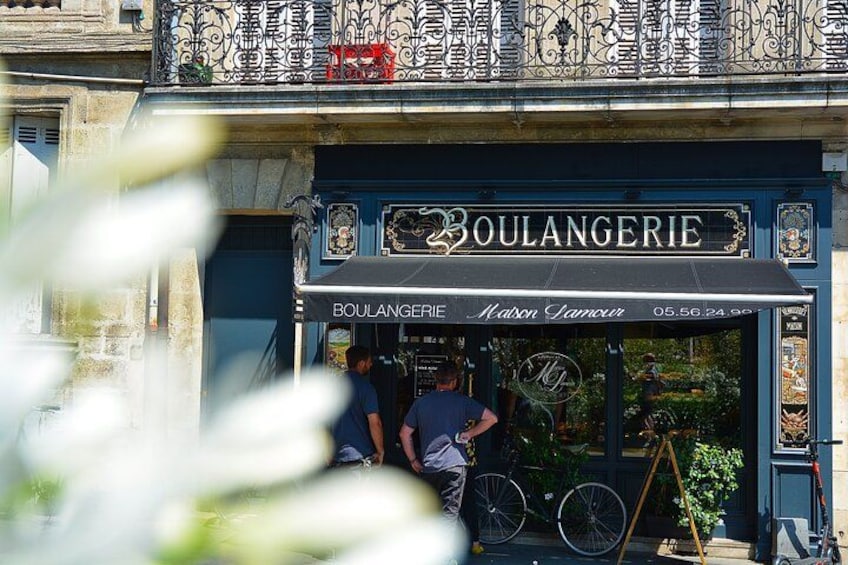 Une boulangerie avec un auvent noir et une enseigne sur laquelle on peut lire « BOULANGERIE ». 2