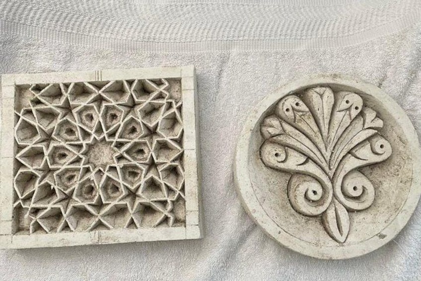Een vierkante steen met een geometrisch patroon en een ronde steen met een bloemmotief. 5