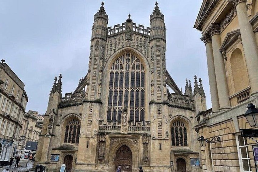 A historic building with intricate Gothic architecture, large arched windows, and detailed stonework. 1