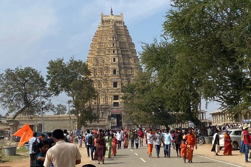 A large crowd of people, a temple with a tiered tower, and trees in the foreground. 4