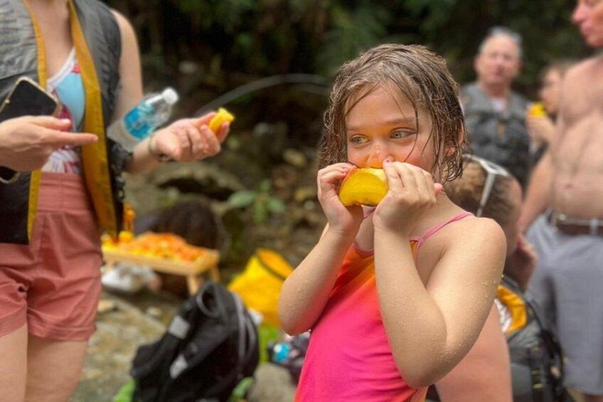 Una persona sostiene un objeto amarillo, quizás una fruta, en un entorno natural con árboles y una mochila a la vista. 2