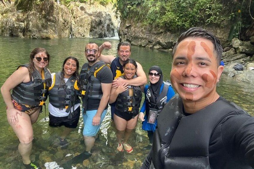 Un grupo de personas en el agua con chalecos salvavidas, de pie en una masa de agua natural rodeada de rocas y vegetación. 5