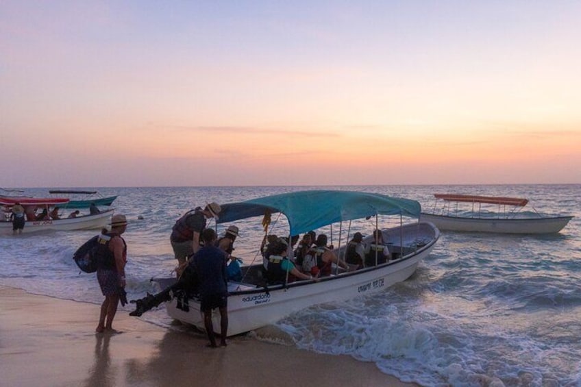 A boat with passengers at a beach during sunset. 5
