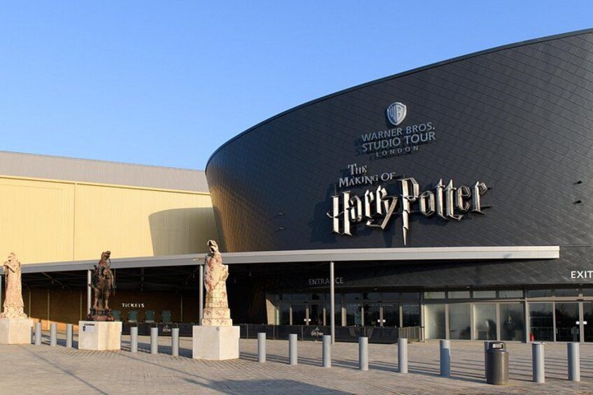 A building with a curved facade, a large sign reading 'Harry Potter,' and statues in front. 2