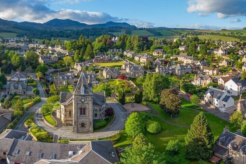 A town with a prominent church, lush greenery, and rolling hills in the background. 4