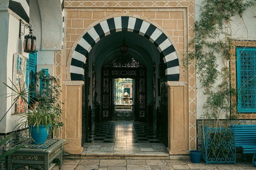 Un callejón estrecho con un arco a rayas que da a un patio. 4
