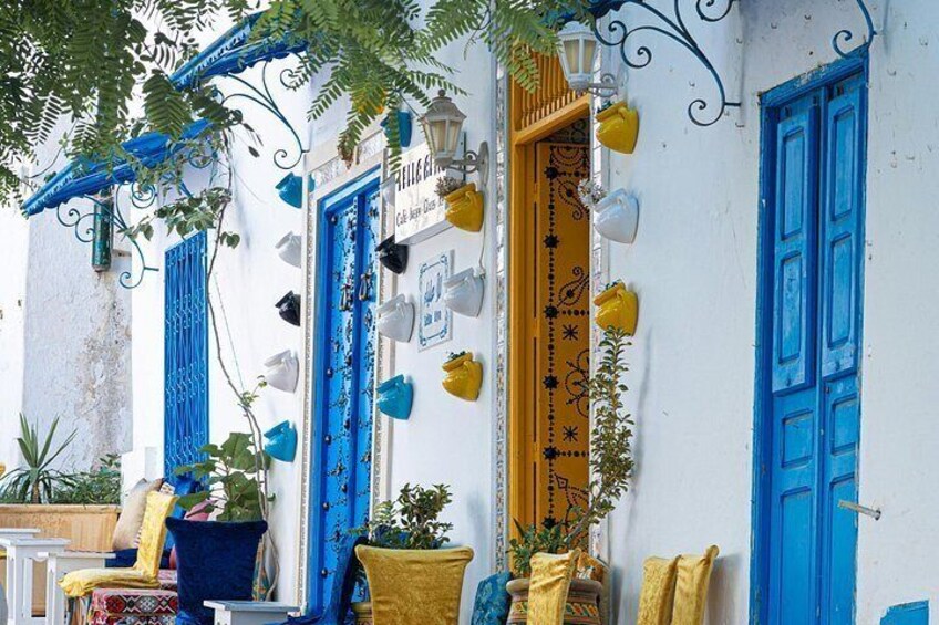 A white building with blue doors and windows, yellow pots, and a yellow chair. 4