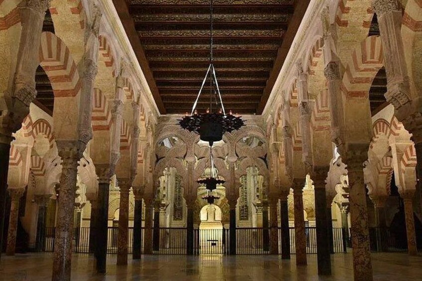 A spacious interior with arches and columns, a hanging chandelier, and a central fountain. 4