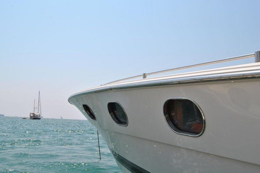 La proa de un barco con un velero a lo lejos. 4