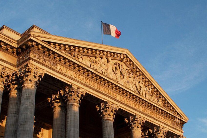 Un edificio imponente con colonne e decorazioni elaborate, una bandiera e un cielo sereno. 5