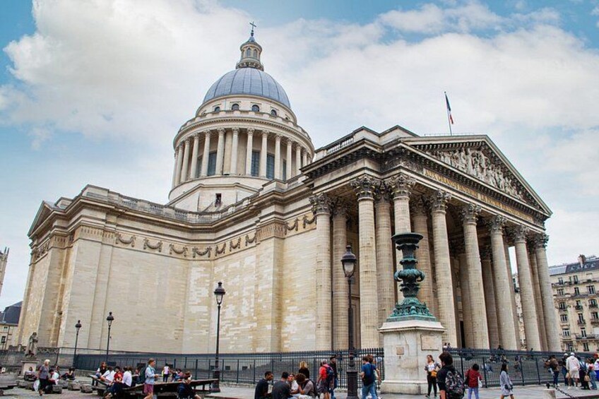 Un grande edificio neoclassico con una cupola e colonne, circondato da una recinzione e persone. 4