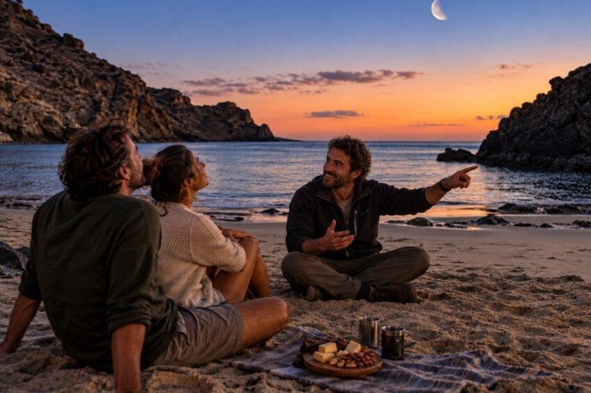 A group of people sitting on a beach at sunset, with a crescent moon visible in the sky. 2
