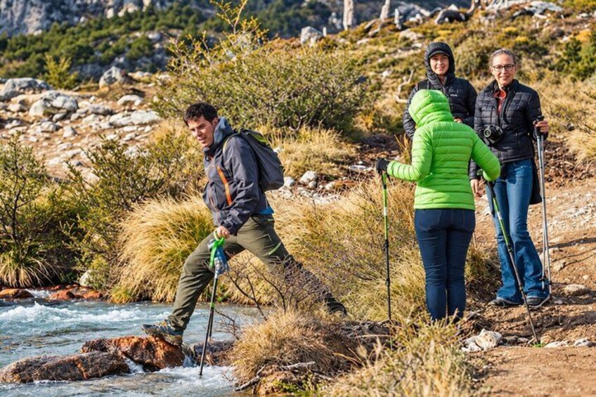 Un groupe de personnes fait une randonnée près d’une rivière, dans une zone rocheuse et herbeuse. 2