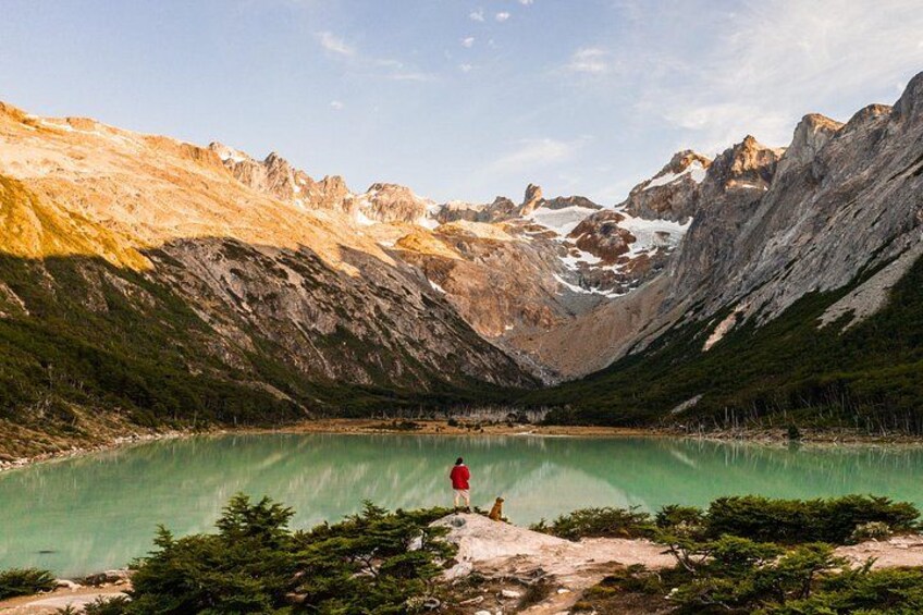 A mountainous landscape with a turquoise lake, rocky terrain, and a person in red clothing. 1