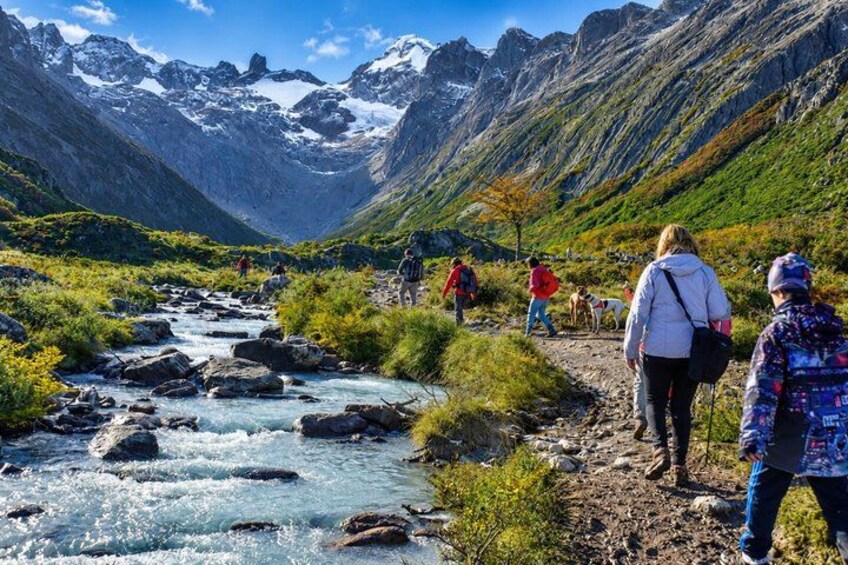 Un paysage montagneux avec une rivière sinueuse, des randonneurs et des sommets enneigés. 5