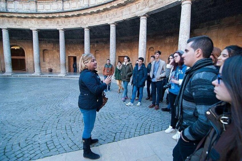 A group of people standing in a courtyard with columns and a circular architectural design. 2