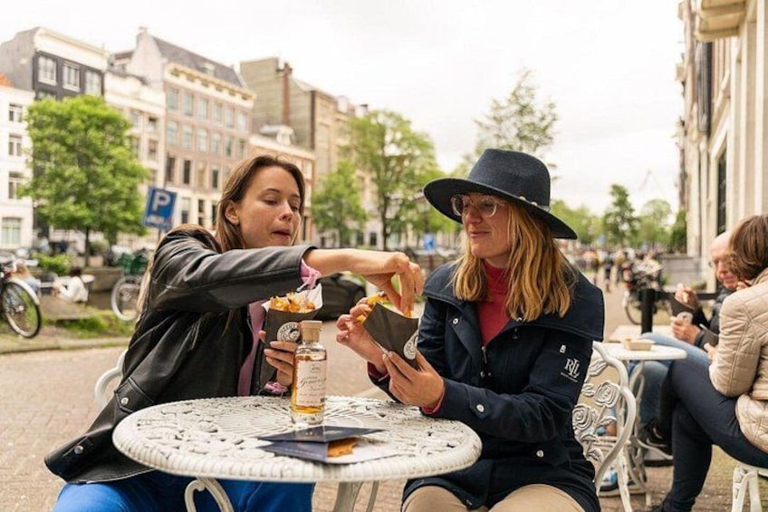 Two people sitting at a round table outdoors, eating food and drinking. 3
