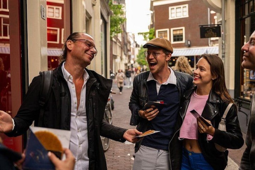 A group of people walking on a street with buildings and a red door. 4