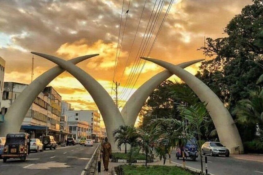 A street with a unique arch structure, vehicles, and buildings. 1