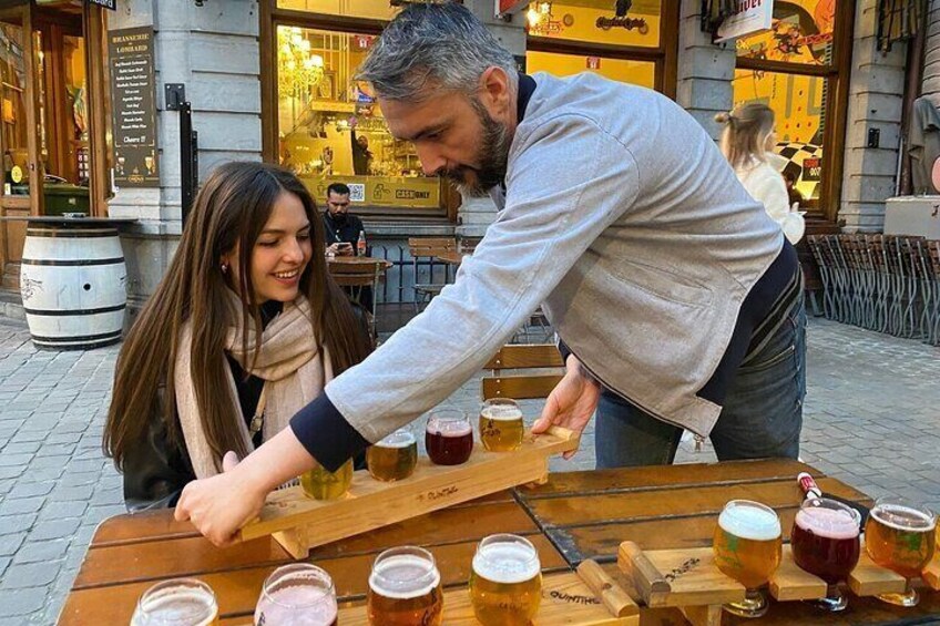 Un hombre sirve cerveza en un vaso sobre una mesa de madera, con varios vasos adicionales y un grifo de cerveza. 2