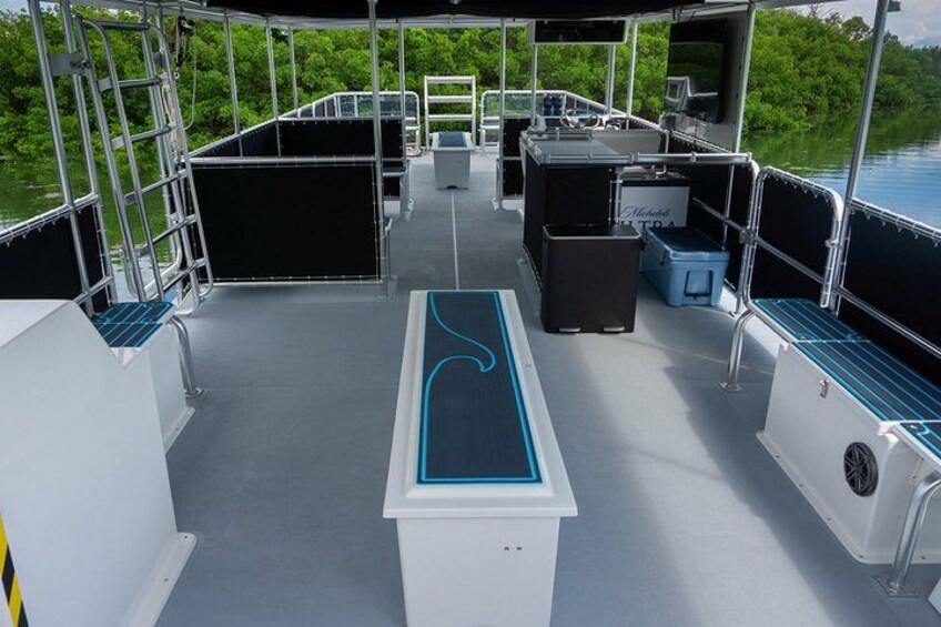 A boat deck with seating, a table, and a railing. 2