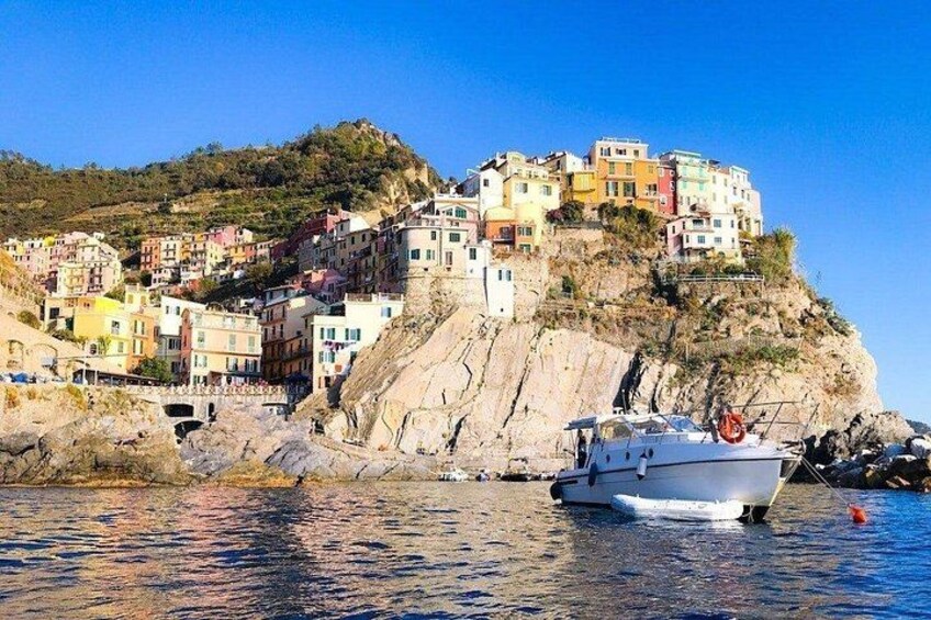 A coastal village with colorful buildings on a cliff, a boat in the water, and rocky terrain. 4