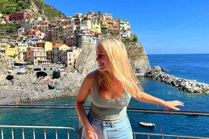 A coastal town with colorful buildings, a rocky shoreline, and clear blue water. 2
