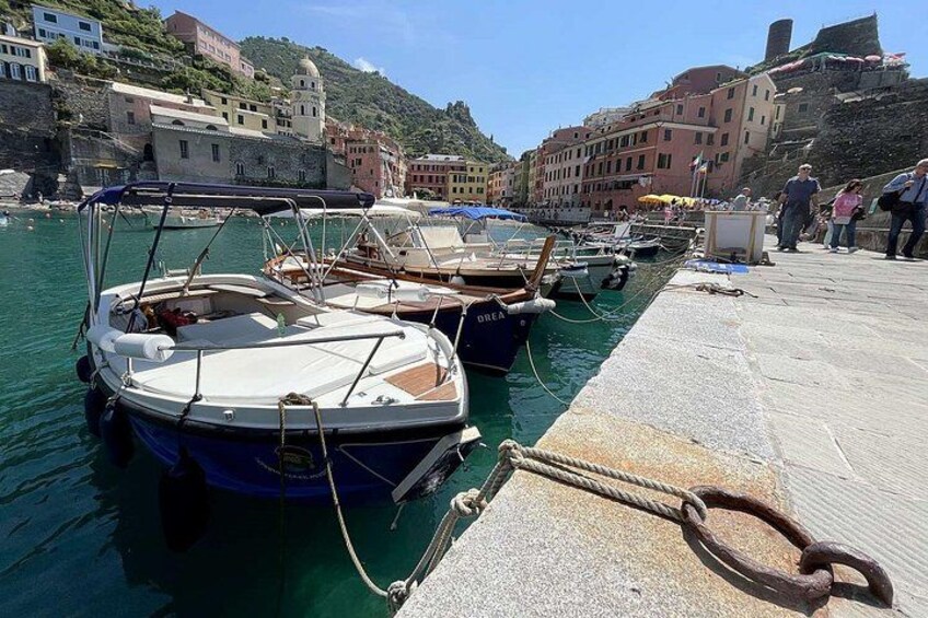 A marina with boats docked, a stone pier, and buildings in the background. 5