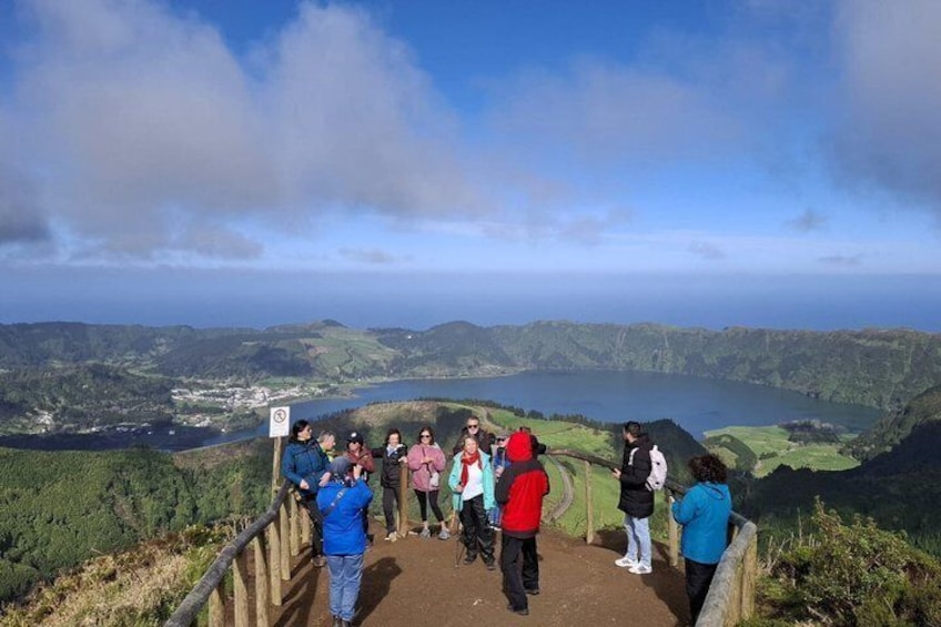 Un grupo de personas en un sendero de senderismo con vistas a un valle y un lago. 2