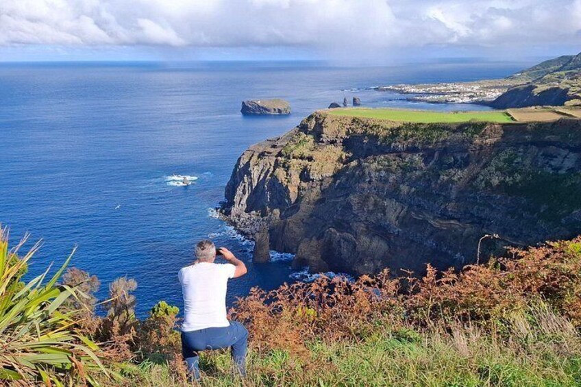En person som fotograferar en klippa vid kusten med havet i bakgrunden. 1