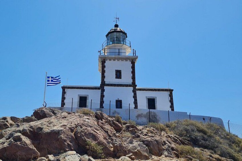 A lighthouse on a rocky hill with a clear blue sky. 4