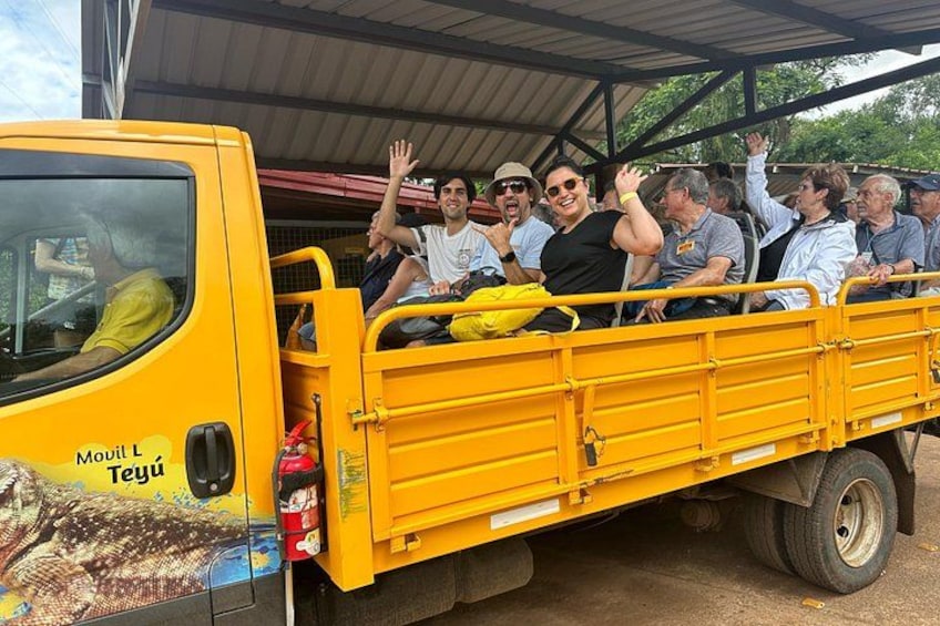 Un camión amarillo con personas en la parte trasera saludando. 1