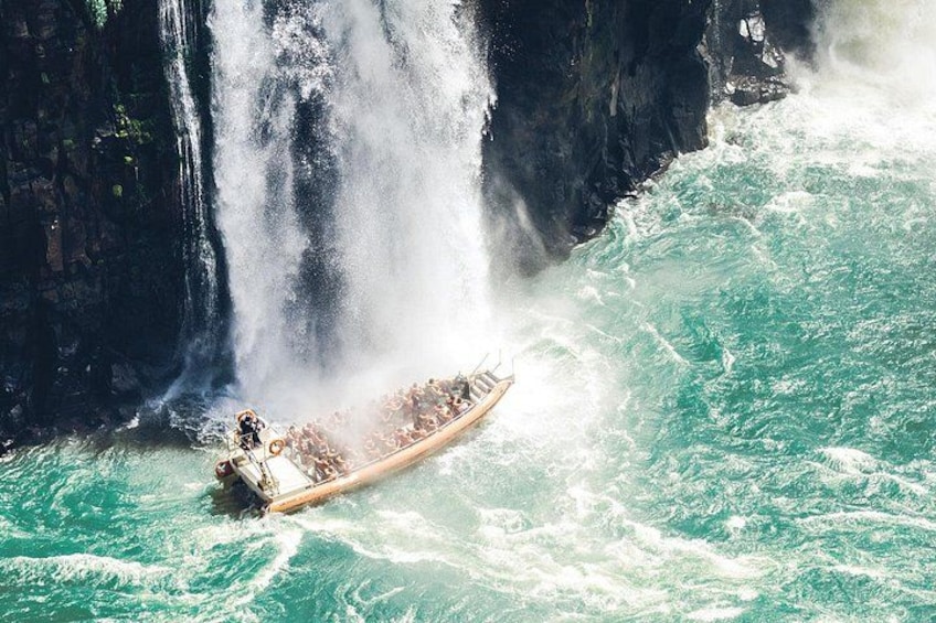 A longboat navigating through turquoise waters with a waterfall in the background. 1