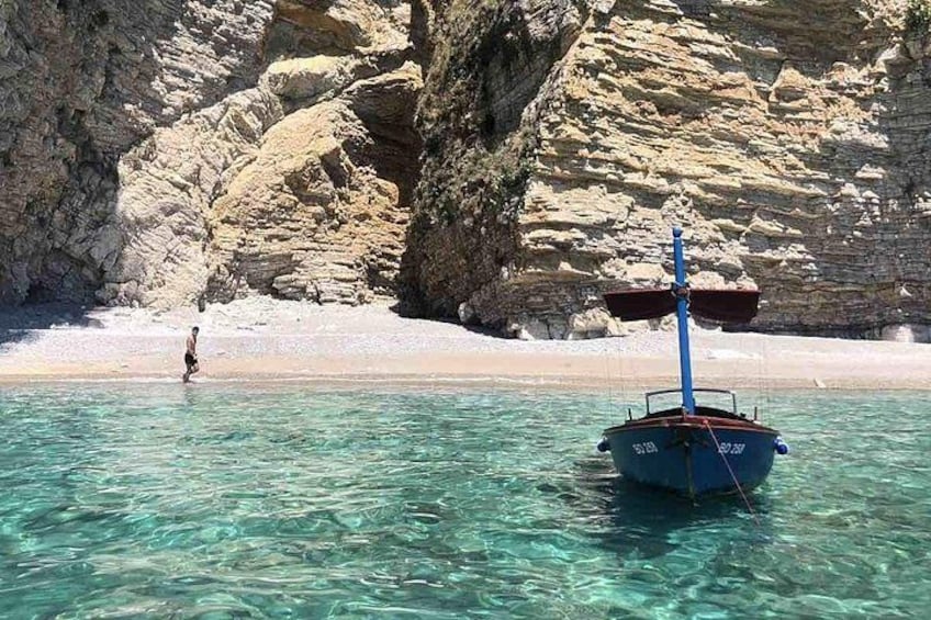 Una barca ancorata vicino a una spiaggia rocciosa con acqua cristallina. 5